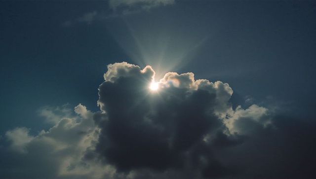 Sun Rays Breaking Through Dark Cumulus Cloud in Dramatic Sky