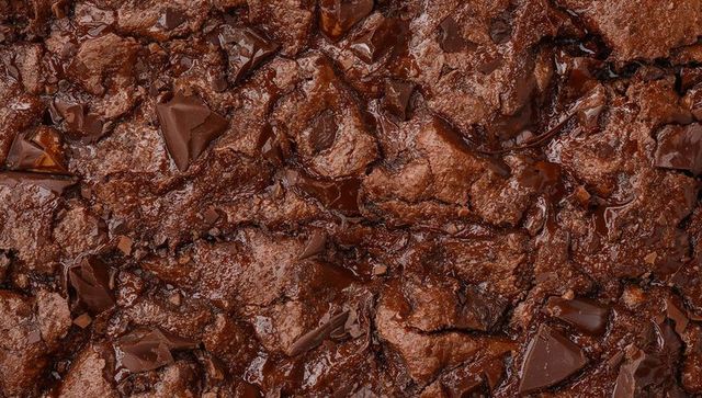 Glistening fudgy chocolate brownie surface with melting chocolate chunks