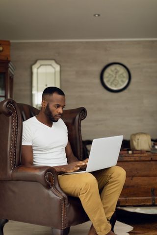 Focused Man Working on Laptop in Cozy Home Environment