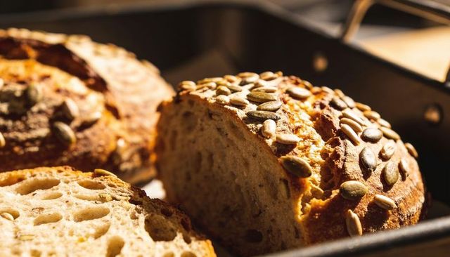 Seeded artisan bread revealing cracked crust and open crumb with pumpkin sunflower seeds