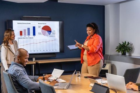 Diverse business team collaborating during data-driven presentation in modern boardroom