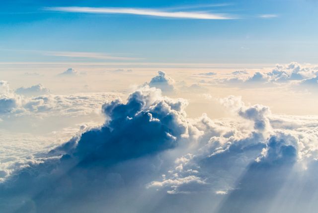 Beautiful cloudscape showing sunlight filtering through soft puffy clouds, creating a serene and tranquil atmosphere. Ideal for backgrounds in websites, inspirational imagery, and illustrations about peace and nature.