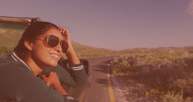 Image of happy biracial woman wearing glasses, driving a cabriolet. travel, holidays and freedom concept digitally generated image.