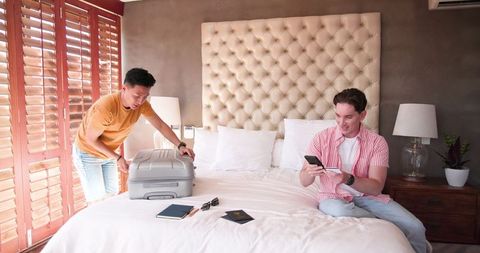 Diverse male couple packing and planning holiday at home