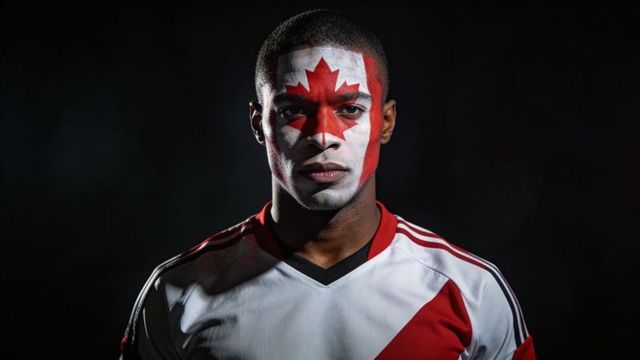 Canadian fan portrait wearing maple leaf face paint and red white soccer jersey, dramatic lighting