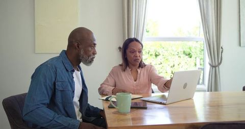 Senior couple managing retirement budget on laptop reviewing bills and financial plans