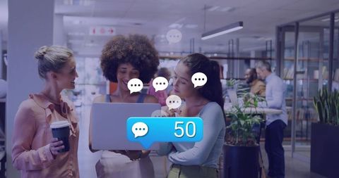 Collaborating around laptop showing 50 message notification in modern open-plan office