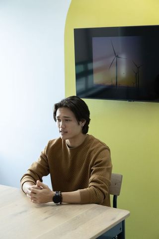 Young asian man discussing renewable energy in modern office with wind turbines on screen