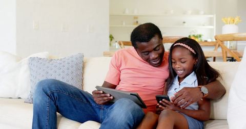 Father and Daughter Enjoying Digital Devices Together at Home