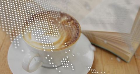 Savoring cappuccino beside open paperback on wooden table for cozy reading moment
