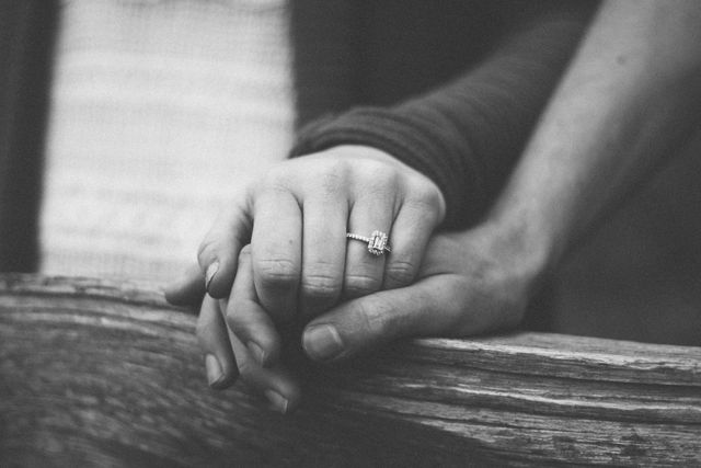 Romantic black-and-white close-up of a couple holding hands, highlighting an engagement ring. Ideal for use in articles and advertisements about love, relationships, commitment, engagements, or wedding planning.
