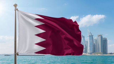 Waving qatar flag billowing over turquoise waterfront with modern doha skyline