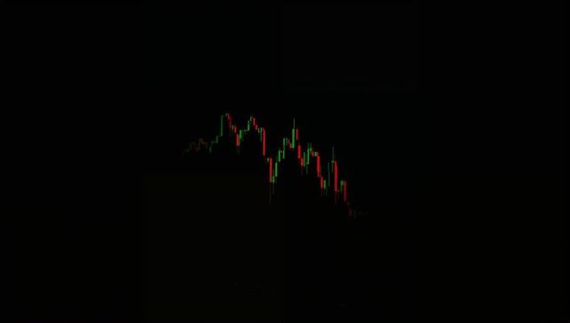 Dark monitor displaying candlestick chart peaking left, declining right, red and green wicks