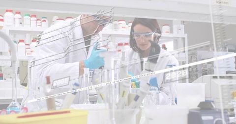Two scientists pipetting at busy lab bench conducting collaborative testing with PPE