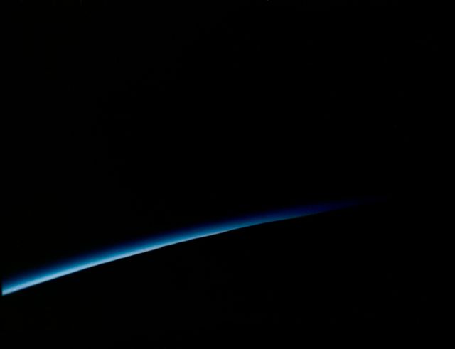 Beautiful image of an orbital sunset taken from the spacecraft Mercury-Atlas 6 by astronaut John Glenn during his historic space mission in 1962. The photo showcases the thin blue line of Earth's atmosphere against the vast darkness of space. Use for articles on space exploration, astronomy, NASA missions, or to illustrate scientific topics related to Earth's atmosphere and space travel.