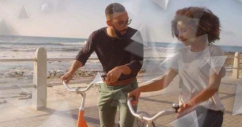 Couple walking bicycles by seaside promenade