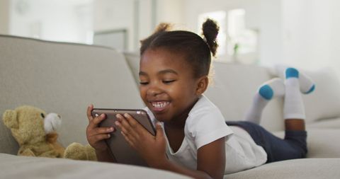Joyful Child Enjoying Tablet on Cozy Sofa at Home - Download Free Stock Images Pikwizard.com