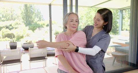 Senior Woman Receiving Arm Stretch from Physiotherapist at Home