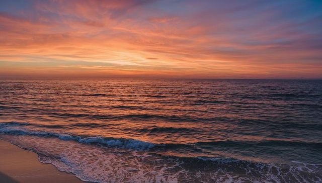 Golden-Pink Sunset Painting Sky Over Calm Ocean With Gentle Shoreline Waves