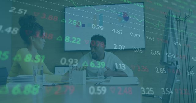 Two colleagues engaging in detailed financial analysis during a business meeting. Chart and stock metrics displayed on background screen. Ideal for corporate strategy presentations, financial analysis illustrations, and economic trend discussions.