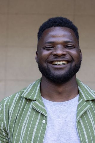 Smiling african man wearing green striped shirt casual closeup headshot for lifestyle use