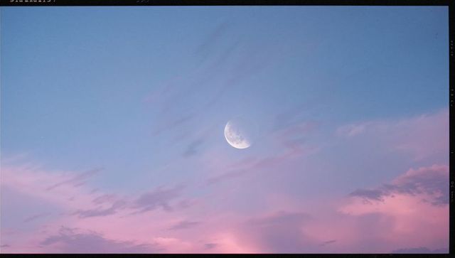 Moon in tranquil twilight with pastel pink and purple clouds