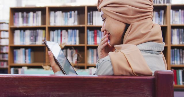 Smiling Woman in Hijab Reading Tablet in Library - Download Free Stock Images Pikwizard.com