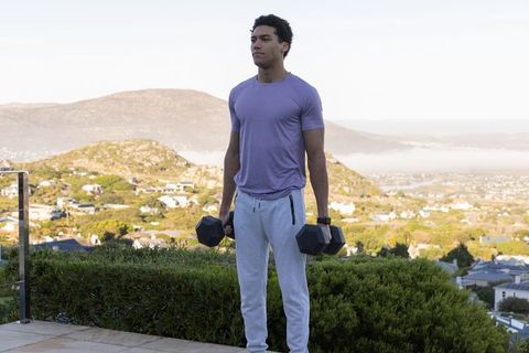 Young Man Exercising with Dumbbells on Outdoor Patio