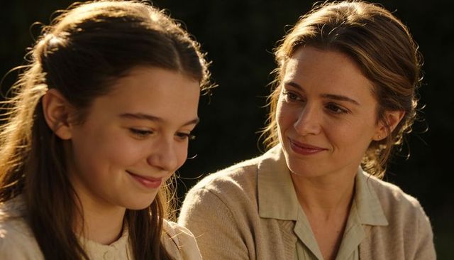 Mother and daughter sharing golden-hour smile, warm backlit bond, intimate family portrait