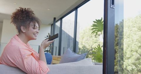 Woman using voice remote control for smart home in bright modern setting