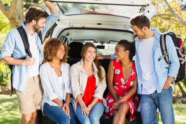 Group of friends sitting in the trunk of a car, enjoying a sunny day outdoors. Perfect for themes related to travel, adventure, friendship, leisure activities, and outdoor fun. Ideal for use in advertisements, travel blogs, social media posts, and lifestyle articles.