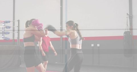 Female boxers sparring in gym throwing punch during intense training session