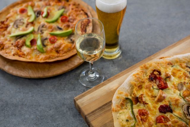 Italian pizzas served on wooden boards with a glass of beer and a glass of wine. Ideal for use in food blogs, restaurant menus, culinary websites, and advertisements for dining establishments. Highlights gourmet dining experience with fresh ingredients and beverages.