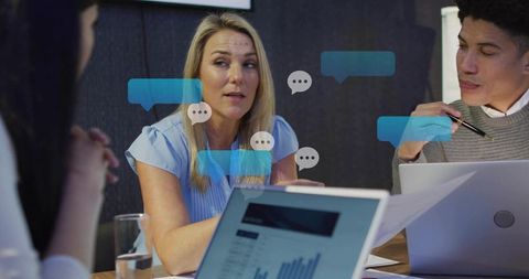 Woman manager guiding team meeting with laptops and chat overlays for office collaboration