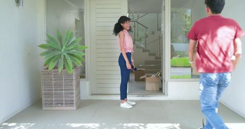 Couple moving into modern suburban home with smiling african american woman on porch