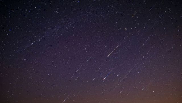 Milky Way Arching across Night Sky with Meteor Streaks, Crescent Moon and Star Trails