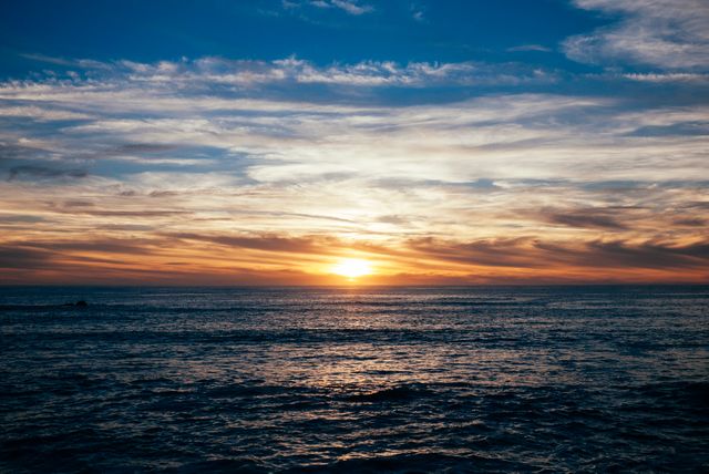 Capturing the peaceful beauty of a sunset over the ocean with calm waves and a colorful sky. Ideal for use in travel brochures, relaxation apps, or inspirational wellness materials. The serene and tranquil nature can also enhance backgrounds, wallpapers, and promotional ads.