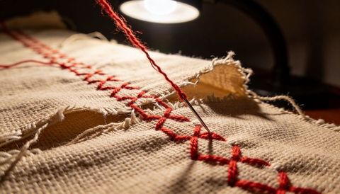 Macro Needle Stitching Red Cross-Stitch on Natural Woven Fabric with Warm Lamp Light Detail