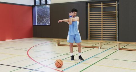 Athlete performing stretch routine at indoor gym before basketball session