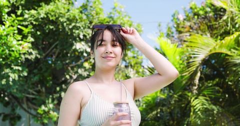 Woman Relaxing in Lush Tropical Garden Holding Refreshing Beverage