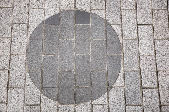 Cobblestone road with a distinct circular pattern in the center. Ideal for use in architectural designs, urban planning presentations, or as a textured background for various projects.