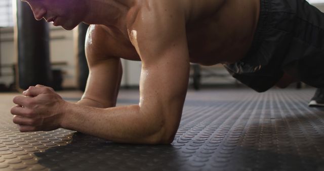 Caucasian muscular shirtless bald man exercising and doing plank. health and fitness training at gym.