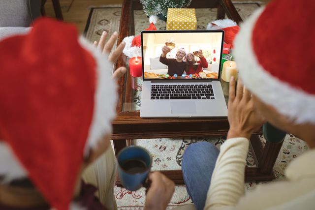 Diverse couple with santa hats having video call with happy caucasian couple - Download Free Stock Photos Pikwizard.com