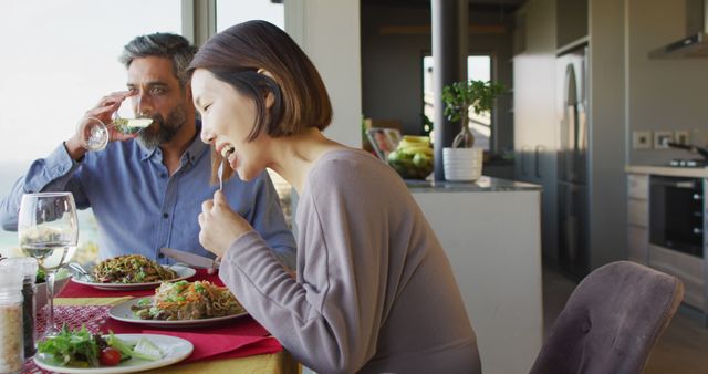 Couple dining together at home, sharing a meal and happy moments. Suitable for use in lifestyle blogs, kitchen and home design websites, or family-oriented advertisements. Can showcase modern kitchen setups or promote healthy, happy living.