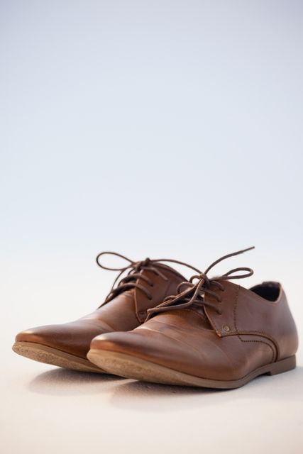 This image features a close-up view of a pair of brown leather dress shoes against a white background. Ideal for use in fashion blogs, online stores, advertisements for men's formal wear, and articles about business attire. The clean background emphasizes the details and craftsmanship of the shoes, making it suitable for high-end fashion promotions.