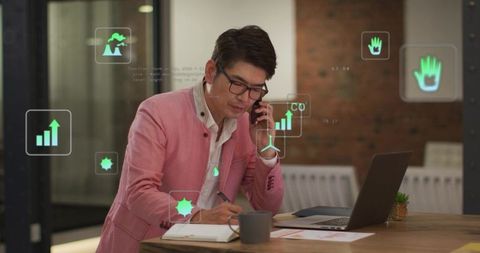 Professional using ar analytics dashboard while making call and writing notes at desk