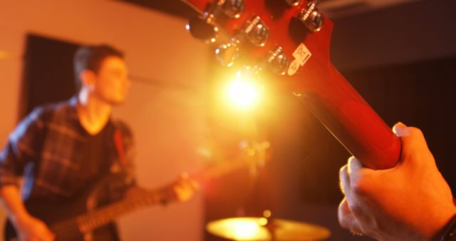 Band playing music in a studio environment with emphasis on guitar. Ideal for use in projects showcasing live music performances, practicing musicians, energetic concerts, or promoting music studios and equipment.