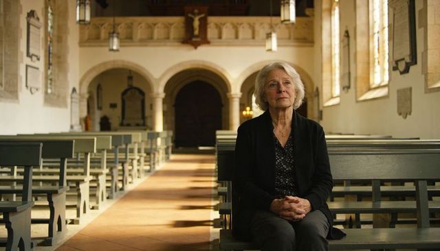 Senior woman sitting in sunlit church pew contemplating faith, reflection and memory
