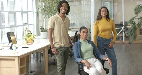 Diverse professionals collaborating in modern open-plan workspace, casual team portrait