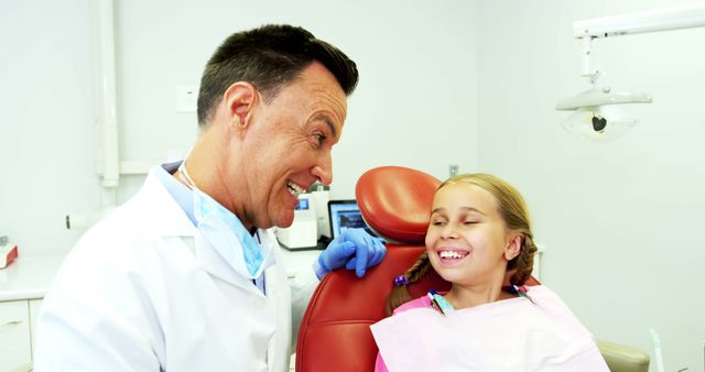 Dentist interacting with cheerful young girl in dental clinic - Download Free Stock Images Pikwizard.com